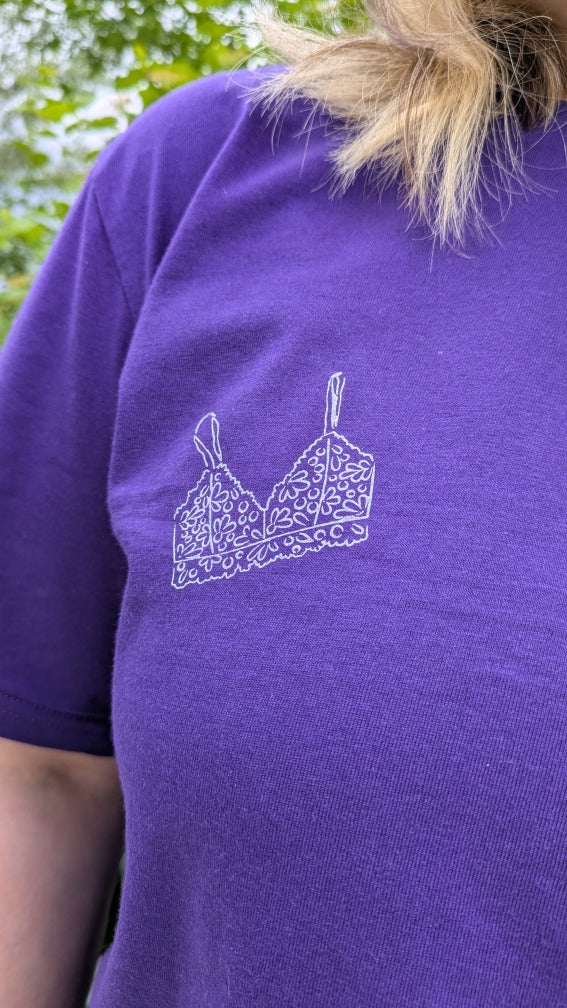 Foto zeigt eine Detailaufnahme von unserem Boobs Club Shirt in violett mit dem Bralette Print auf der Vorderseite.