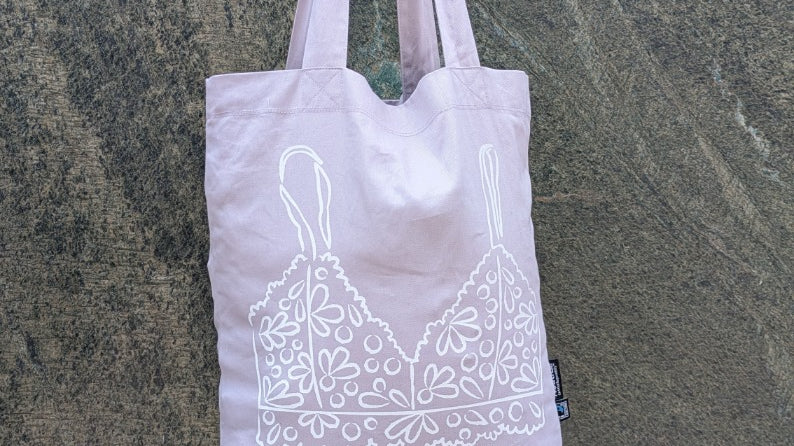 Foto zeigt die Baumwolltasche mit Fokus auf den Print auf der Rückseite mit dem Bralette Print