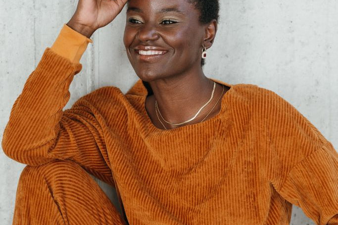 Portraitbild vom Model mit dem Chloé Pullover in Ocker. Sie blickt verträumt neben der Kamera vorbei.
