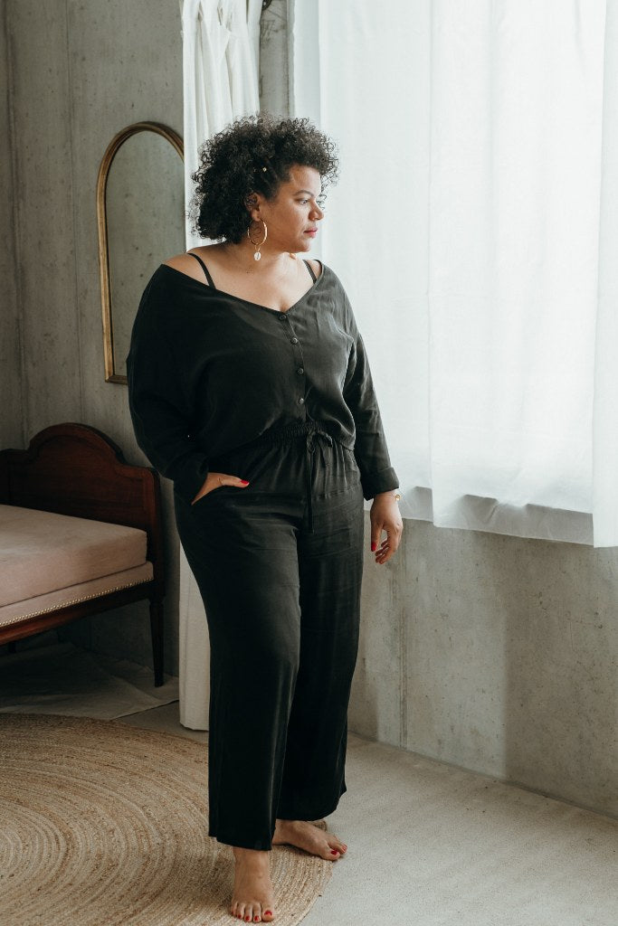 Woman wearing vegan silk pyjamas and standing in front of the window.