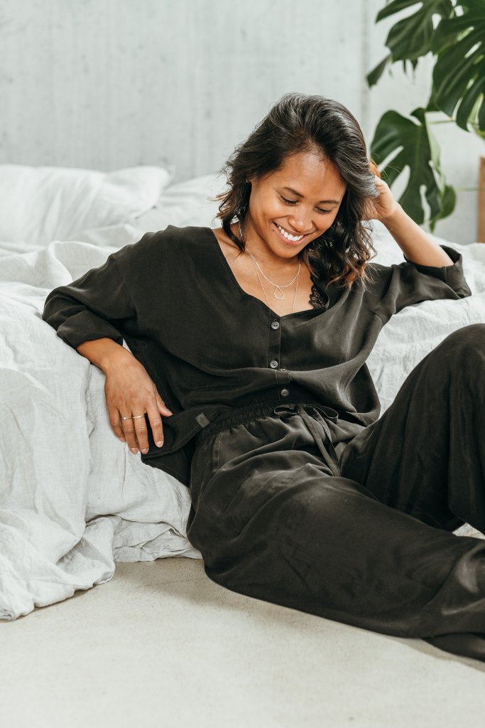Woman wears black pyjamas and smiles