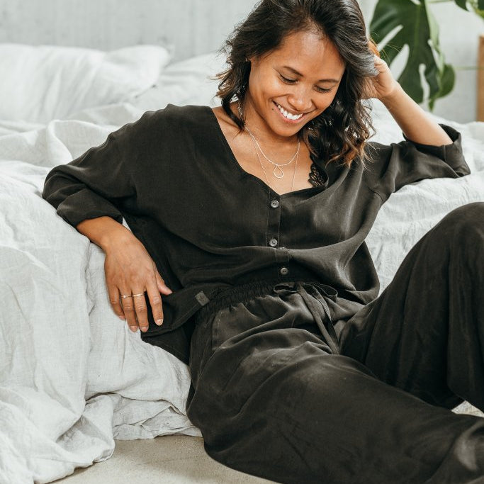 Woman wears black pyjamas and smiles