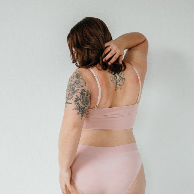 la modella con i tatuaggi posa con il reggiseno Emma e gli slip Emma realizzati con materiali sostenibili