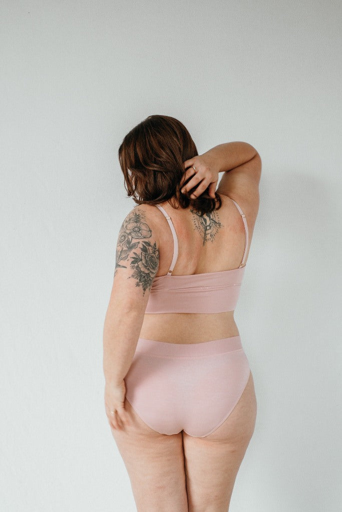 la modella con i tatuaggi posa con il reggiseno Emma e gli slip Emma realizzati con materiali sostenibili