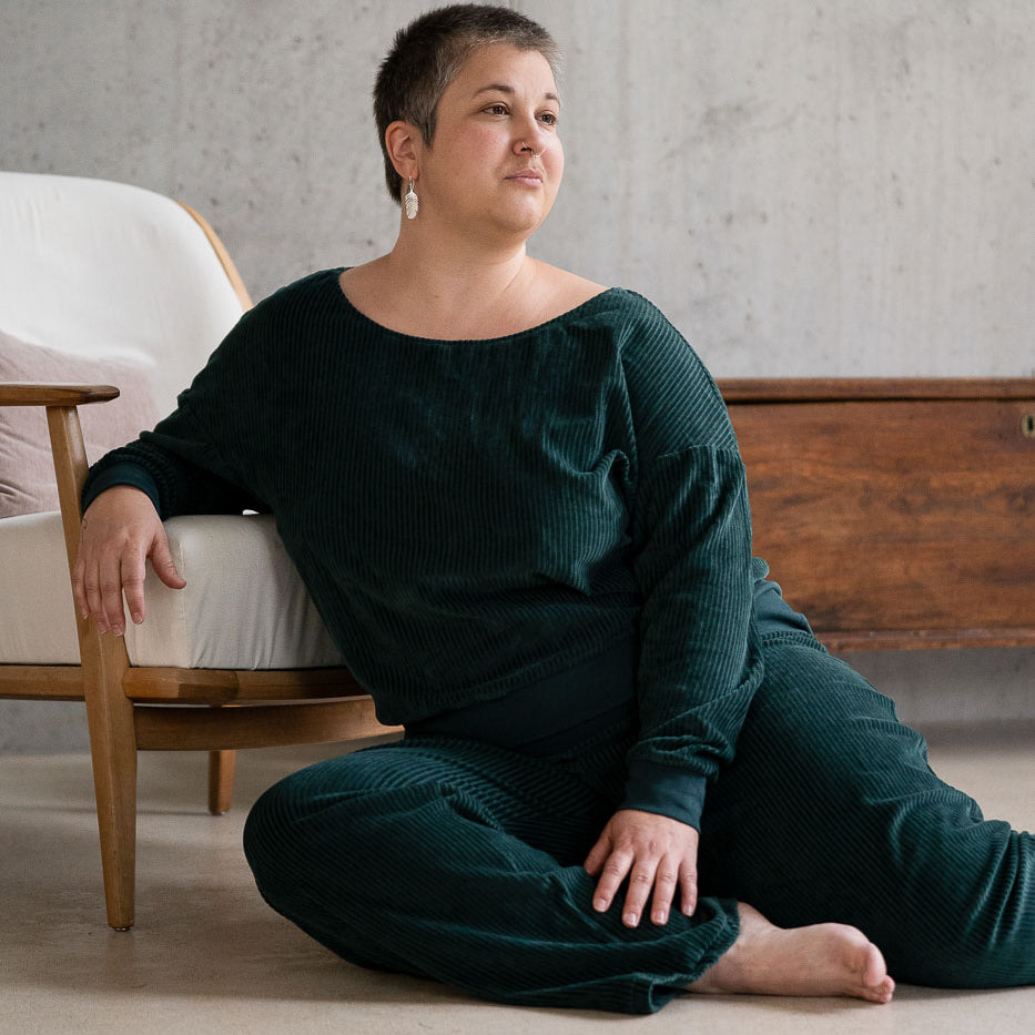 Model sitzt im jadegrünen Pyjama auf dem Boden, lässig auf einem Sessel abgestützt