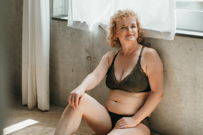 Model sitzt am Boden und trägt das Gisele Set. Den Rücken hat sie an der Wand angelehnt.