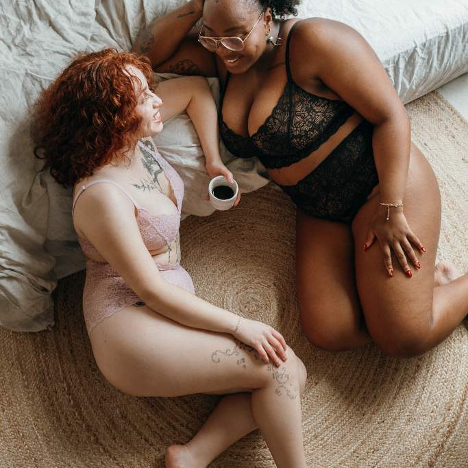 two women talking to each other and posing in beautiful lacy lingerie