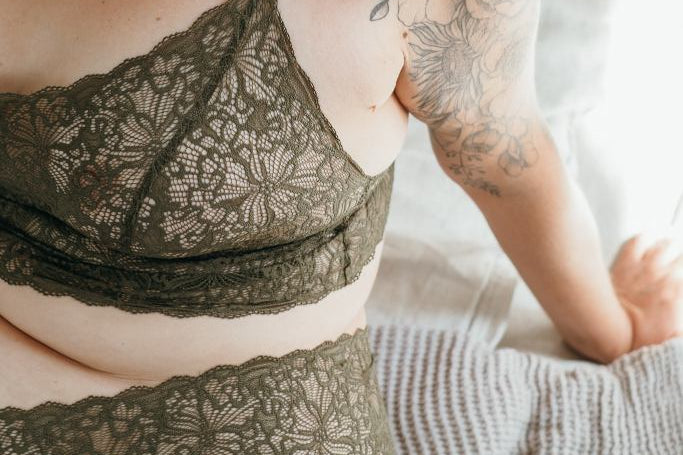Model trägt Joy Set in der Farbe Olive. Sie sitzt auf dem Bett.