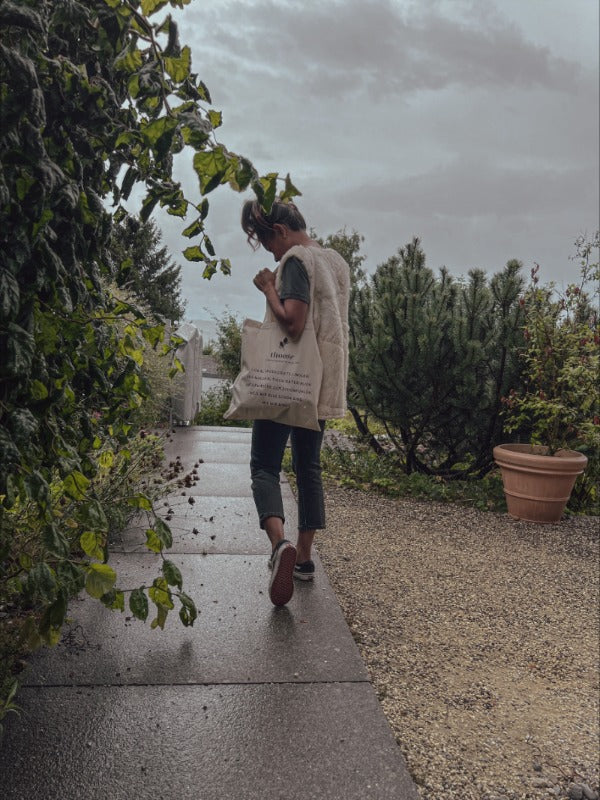 Una donna cammina con disinvoltura con una borsa di stoffa di thoughts of september sulla spalla.