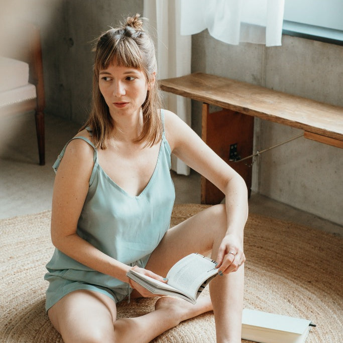 The woman holds a book in her hand and shows herself in the Kat top in the color summer mint