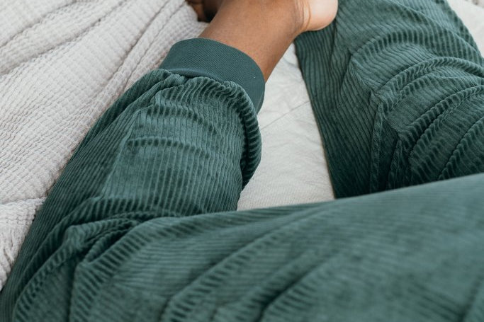 Detailaufnahme von der Kelly Hose in Jadegrün. Model liegt bauchlinks auf dem Bett.