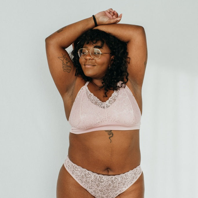 the woman holds her arms above her head and presents locally produced underwear