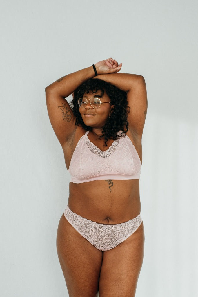 the woman holds her arms above her head and presents locally produced underwear