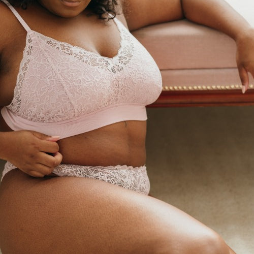 the model sits on the floor and leans against the couch in the beautiful Dessou