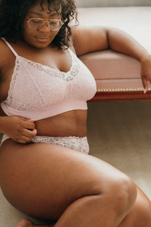 the model sits on the floor and leans against the couch in the beautiful Dessou