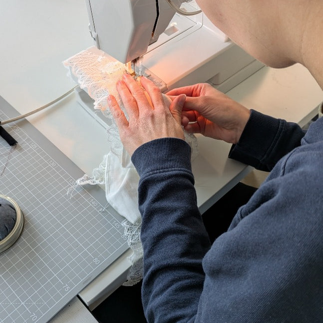 Foto zeigt eine unserer Workshopteilnehmerinnen von hinten an der Nähmaschine. Sie näht gerade an ihrem Slip.
