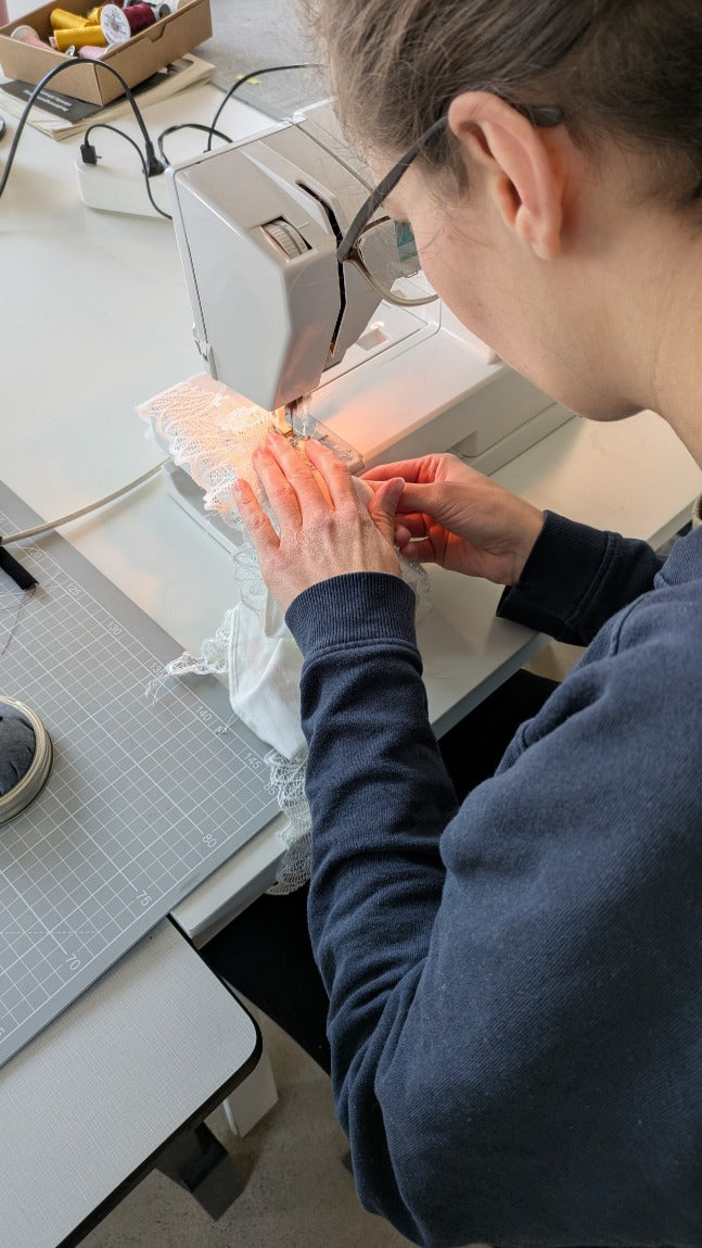 Foto zeigt eine unserer Workshopteilnehmerinnen von hinten an der Nähmaschine. Sie näht gerade an ihrem Slip.