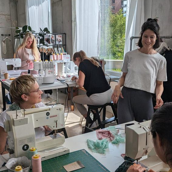 Kira explains the next step to the participants in a sewing workshop