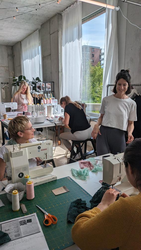 Kira explains the next step to the participants in a sewing workshop
