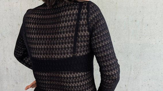 Model trägt den Paula Spitzenpulli und steht mit dem Rücken zur Kamera.