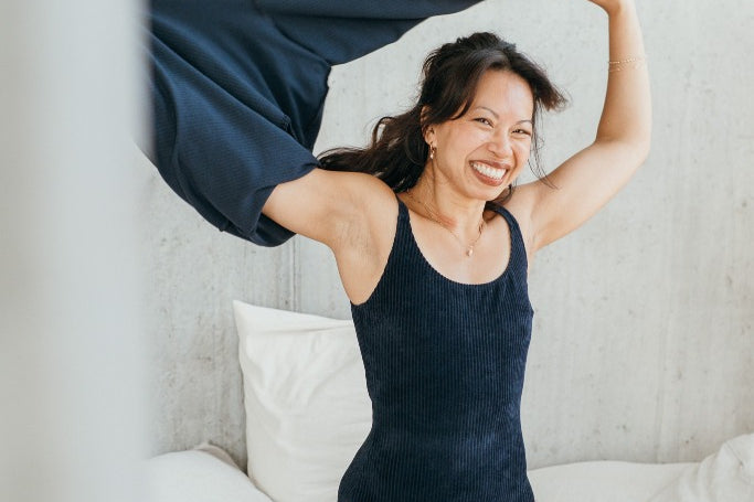 Model trägt das dunkelblaue Ronja Body und zieht sich gerade den dunkelblauen Chloé Pulli aus.