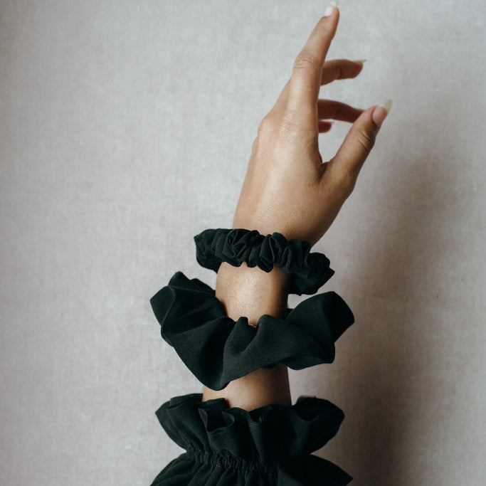 Tre diversi scrunchies realizzati con materiali di scarto su un polso.