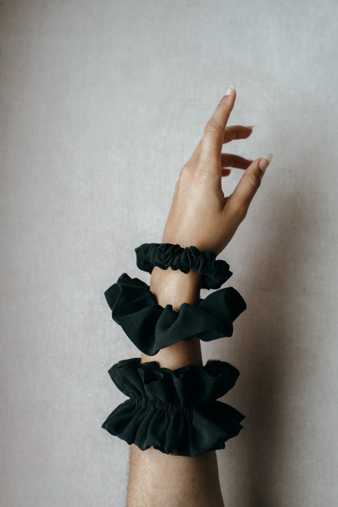 Tre diversi scrunchies realizzati con materiali di scarto su un polso.