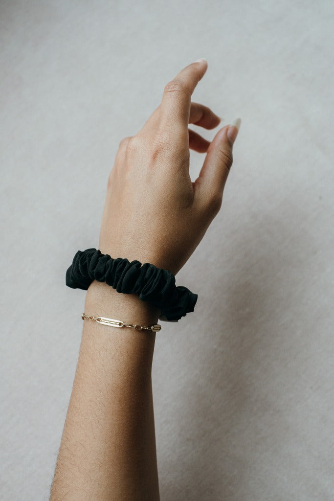 fine scrunchie on wrist with gold bracelet.