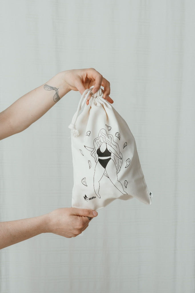Hands holding wash bag with illustration of dancing woman in underwear.