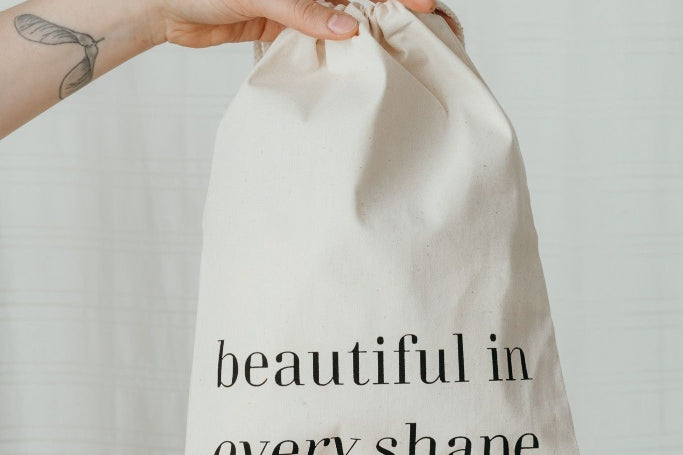 Hand hält Waschbeutel mit Aufdruck "beautiful in every shape"