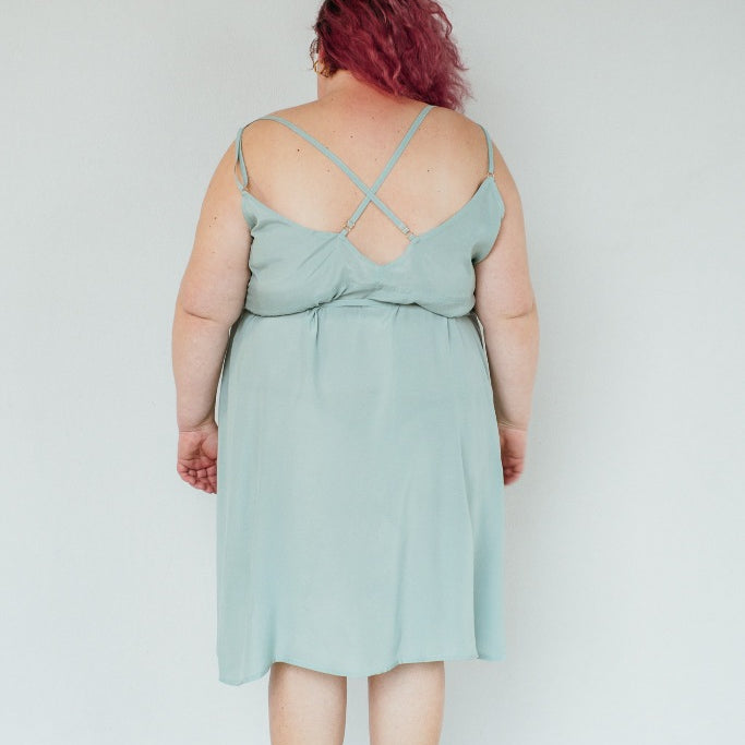 The model stands with her back to the camera and poses in the Zia dress in the color summer mint