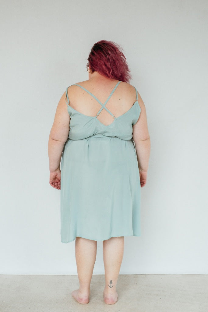 The model stands with her back to the camera and poses in the Zia dress in the color summer mint