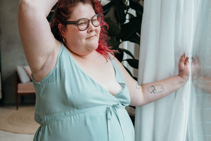 le mannequin aux cheveux roux pose à la fenêtre vêtu de la robe Zia 
