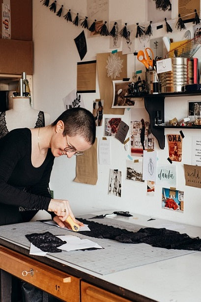 Foto zeigt Zippora am Schnitttisch. Sie schneidet Spitze für ein Bralette zu.