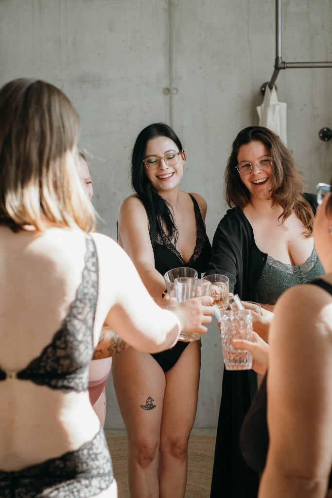 Die Sisterhood Ladies prosten sich gegenseitig zu und posieren dabei in Lingerie