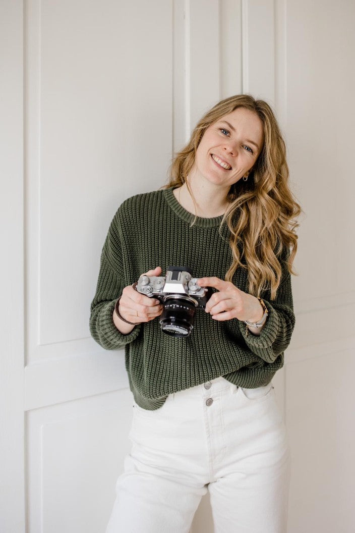 Stefanie Meier hält ihre Kamera in den Händen und lächelt.