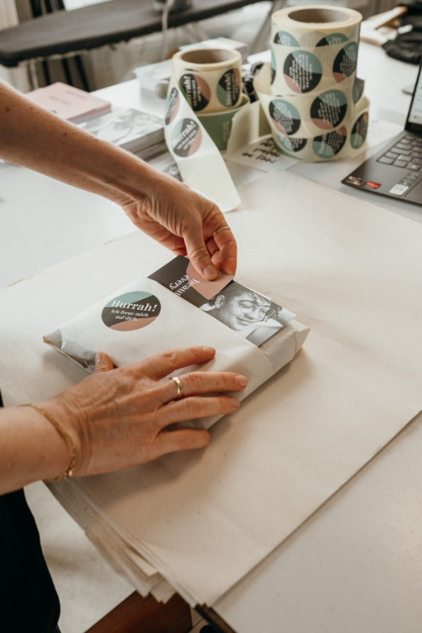 jemand verpackt Unterwäsche und dekoriert sie mit Flyers