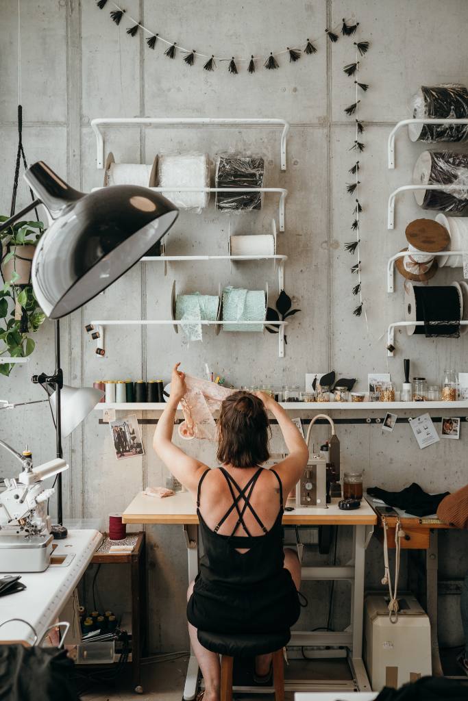 Zippora Marti sitzt an Nähmaschine und kontrolliert ein rosa Bralette