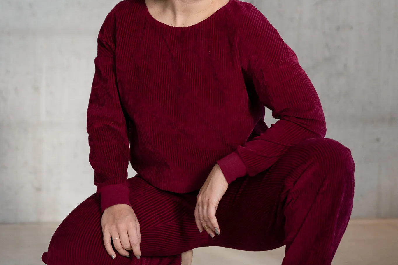 Model ist in einer tiefen Hocke und trägt den Chloé Pulli und die Kelly Hose in Ruby Red.