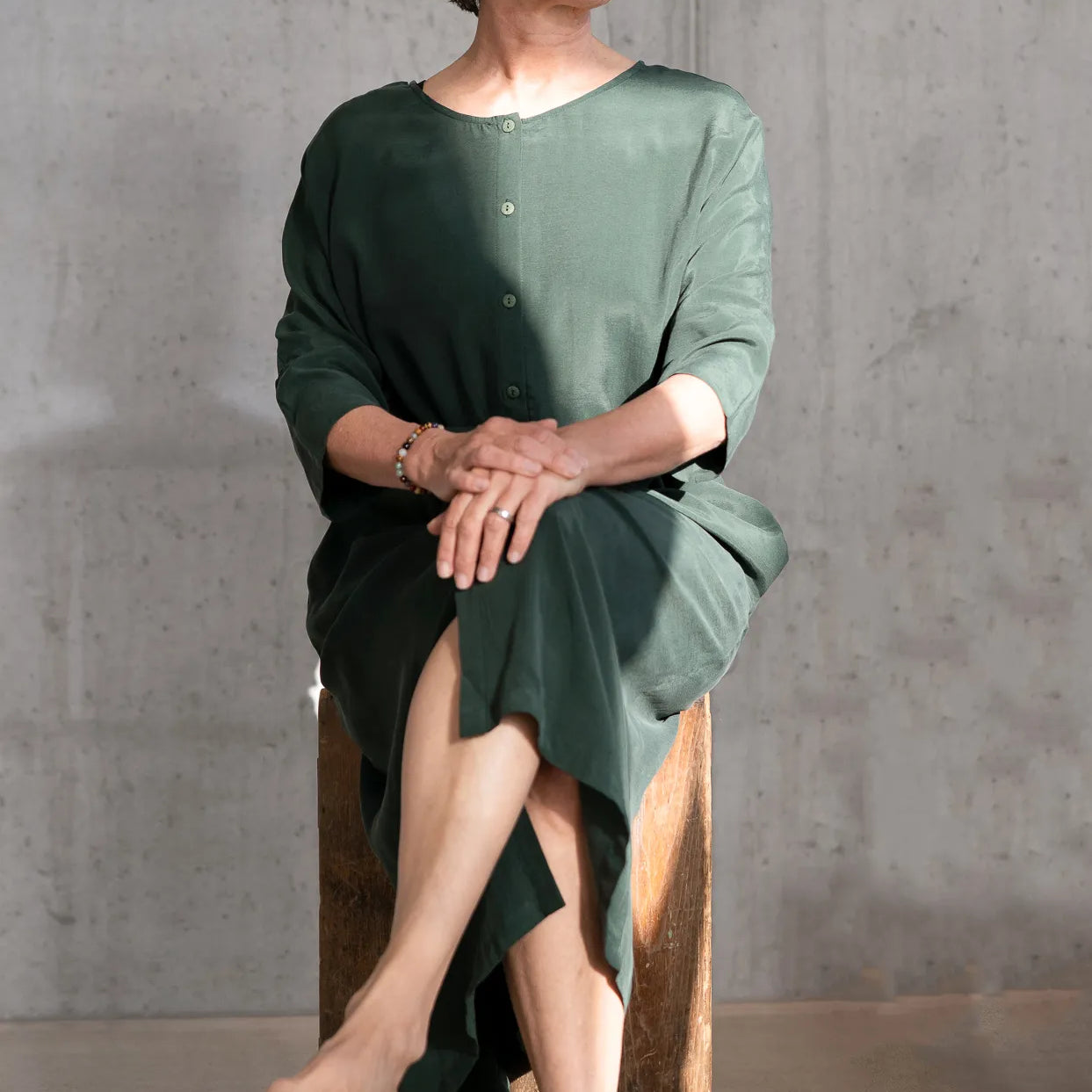 Frau sitzt in der Sonne uns trägt das Grüne Kleid "Kim" von thoughts of september