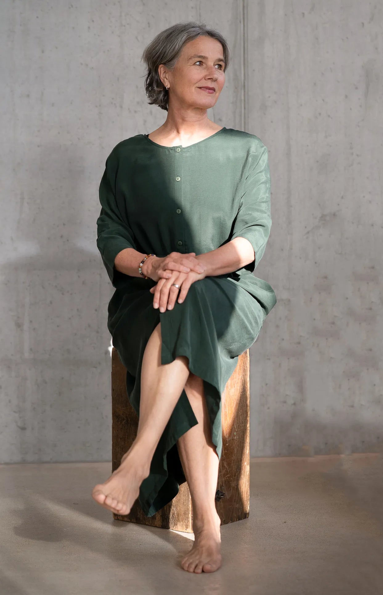 Frau sitzt in der Sonne uns trägt das Grüne Kleid "Kim" von thoughts of september