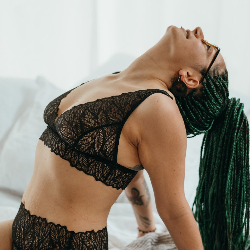 Woman with long blue hair wears bra and panties, she supports herself and leans head on neck