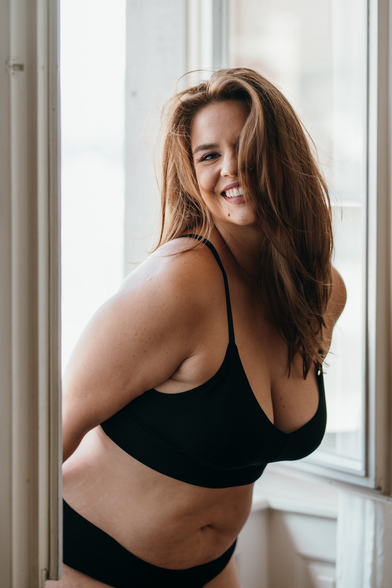 Model schwingt die Haare und lächelt. Sie trägt Basic Bralette und Unterhose aus TENCEL™