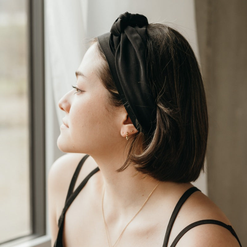 Woman looks out of the window and wears a black hairband.