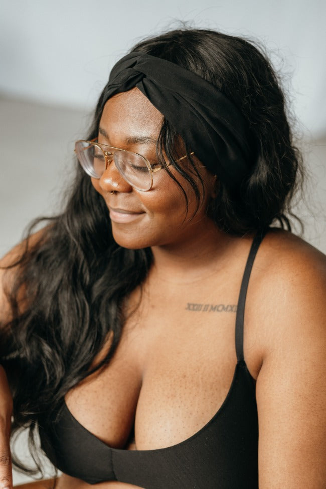 Woman wears black Bralette and has a hair band tied in her hair.
