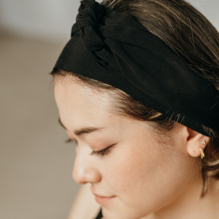 Woman with long hair tied back with a black hair band.
