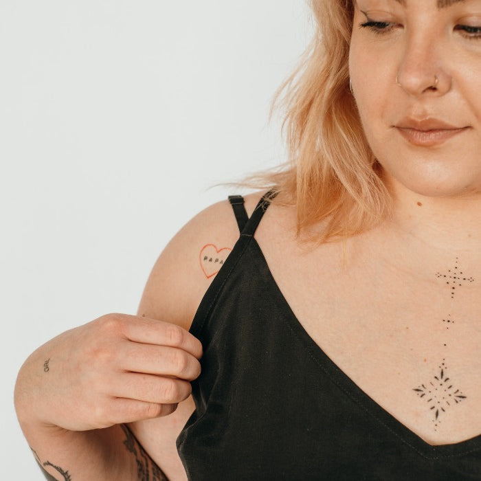 Woman with tattoos wears top with fine straps.