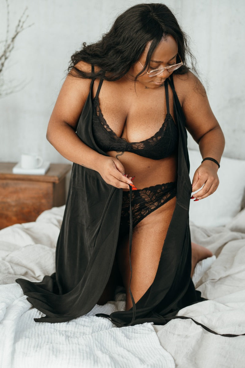 Woman tying up the black negligee made of cupro by thoughts of september