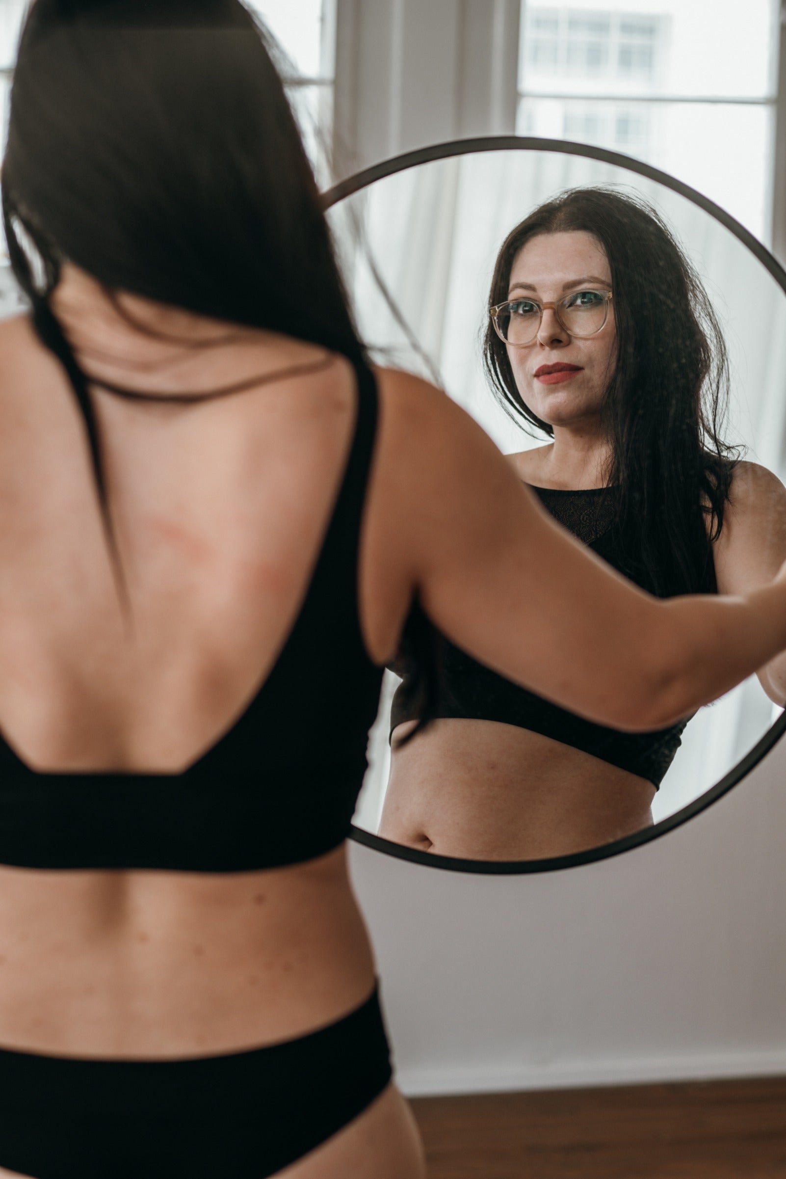 Une femme tient un miroir dans sa main et regarde à l'intérieur. 