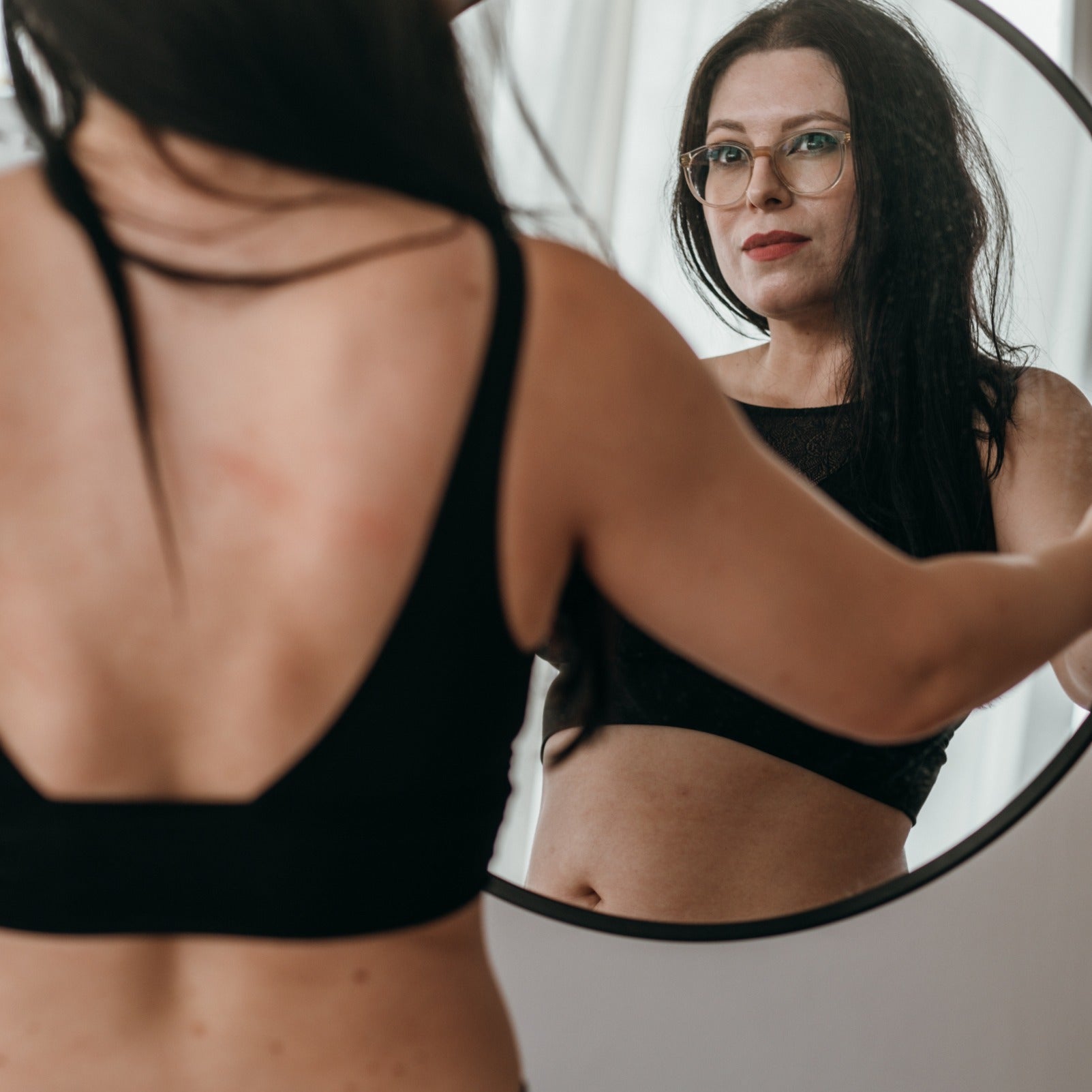 Woman holds a mirror in her hand and looks into it. 